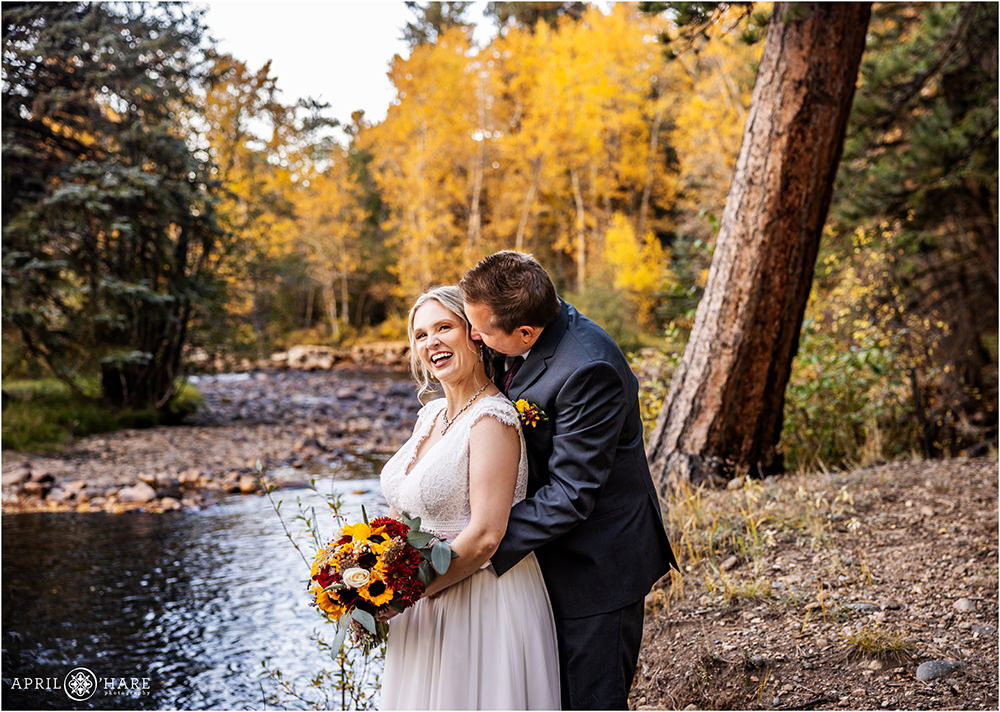 Bride laughs with her groom next to the Big Thompson River on their fall color wedding day at Romantic Riversong Inn