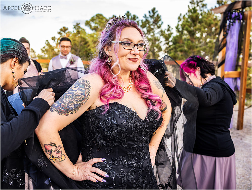 Bride wearing a black jeweled tiara and a black wedding dress gets bustled at her Colorado wedding