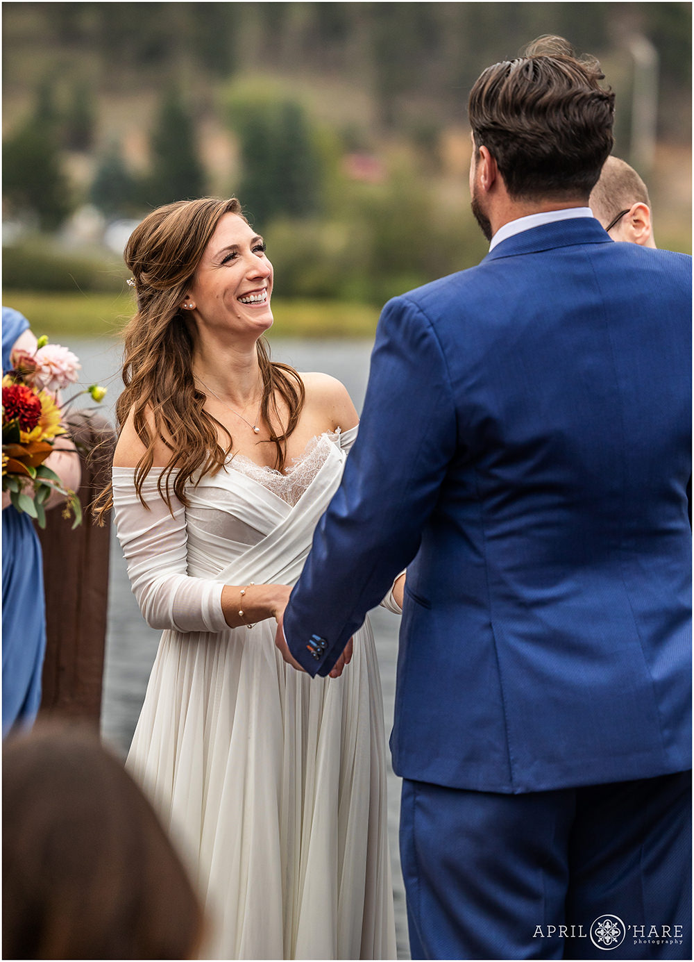 Bride smiles up at her groom as they say their vows on the backdeck at Evergreen Lake House