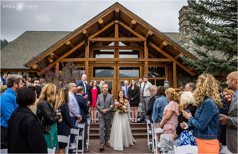 Bride cries as she walks down the aisle with her dad at Evergreen Lake House