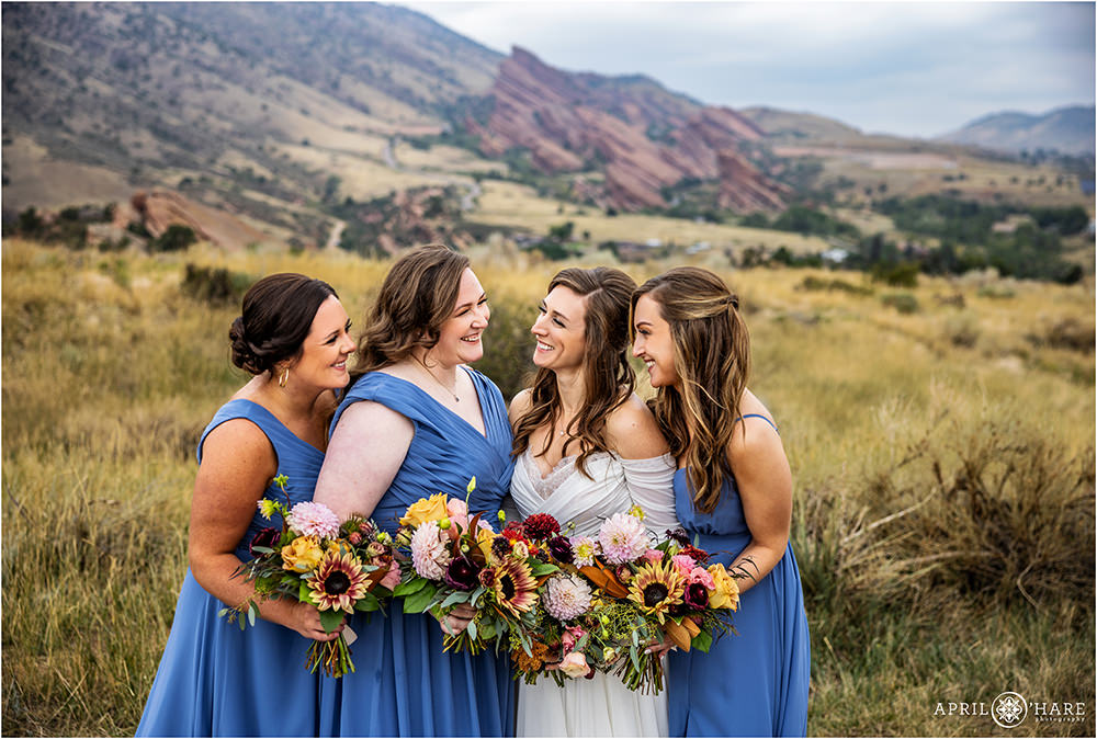 Bride with her bridesmaids at East Mount Falcon Trailhead with Red Rocks off in the distance