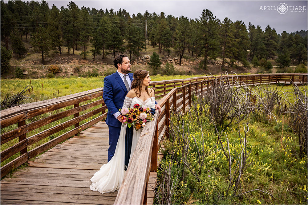 Couple photographed on the wood boardwalk at Evergreen Lake House in Colorado on their September wedding day