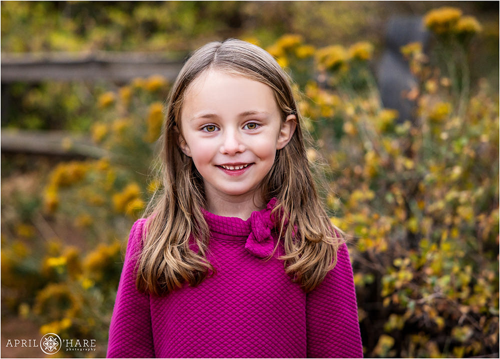 Sweet photo of a little girl wearing a pink dress with fall color backdrop at East Mount Falcon in Colorado