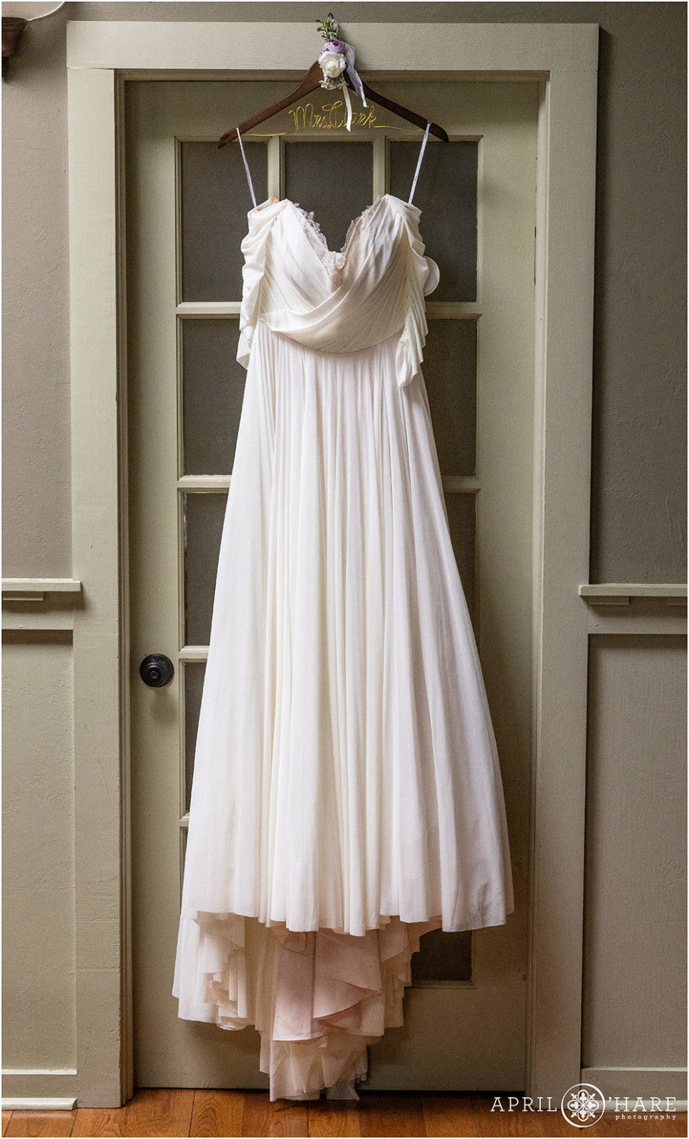 Gown from Emma & Grace Bridal hangs in a doorway at an Evergreen Colorado wedding