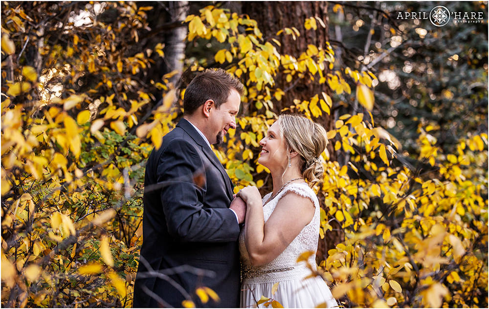 Bride and groom hold hands as they look at each other in the fall color at Romantic Riversong Inn