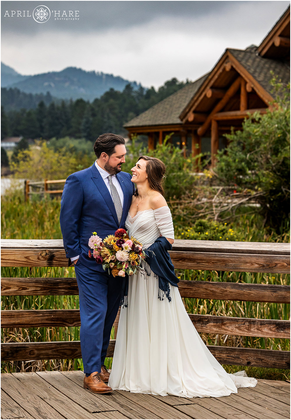 Gorgeous Wedding portrait on the wooden boardwalk with Evergreen Lake House in the backdrop on a stormy fall wedding day