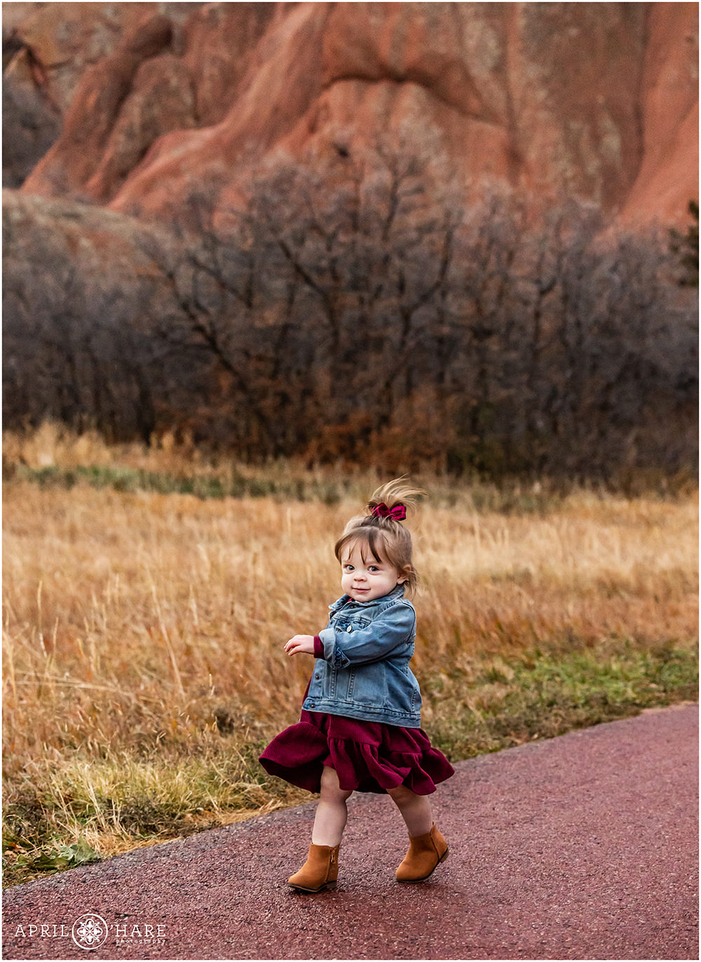 Cute toddler girl walks down the road at Roxborough State Park During Fall