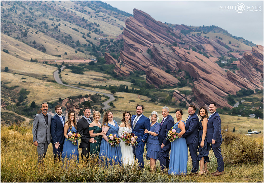 Bride and groom pose for a portrait with their entire family with Red Rocks off in the Distance at East Mount Falcon Trailhead