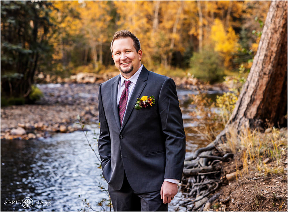 Groom portrait with fall color backdrop next to a pretty mountain stream at Romantic Riversong Inn