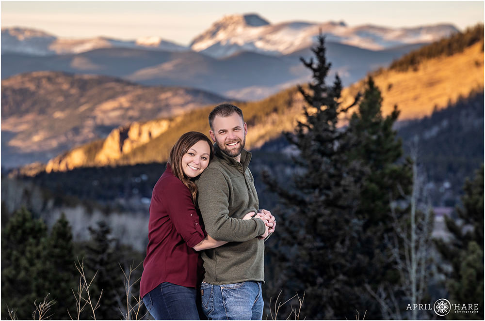 Couple snuggles in front of a pretty mountain backdrop in Evergreen CO