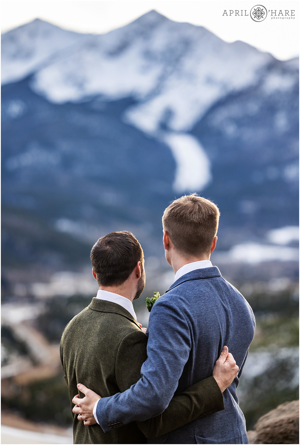 Two grooms hug as they look out at the beautiful mountain view at Sapphire Point