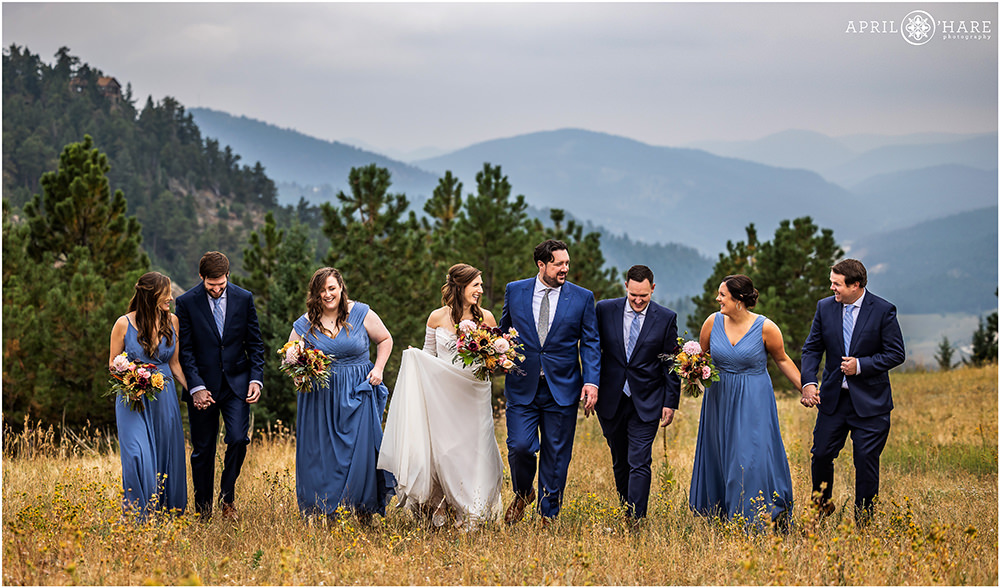 Couple and their wedding party walk through the mountain meadow at West Mount Falcon in Colorado