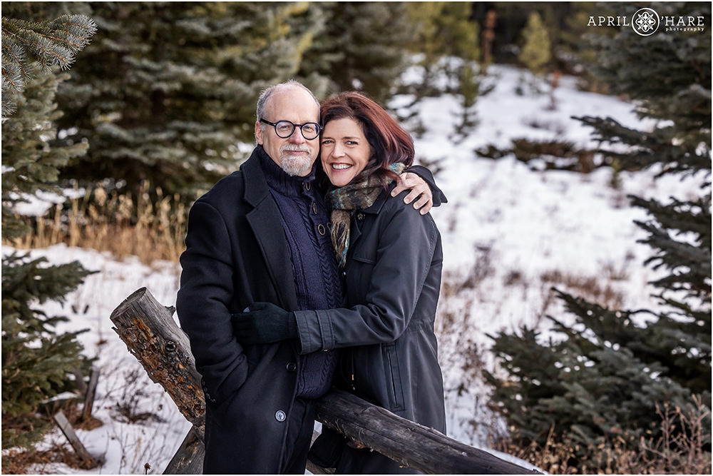 Couple married for 30 years poses together in a pretty Colorado mountain scenery with snow and evergreen trees in Evergreen during winter