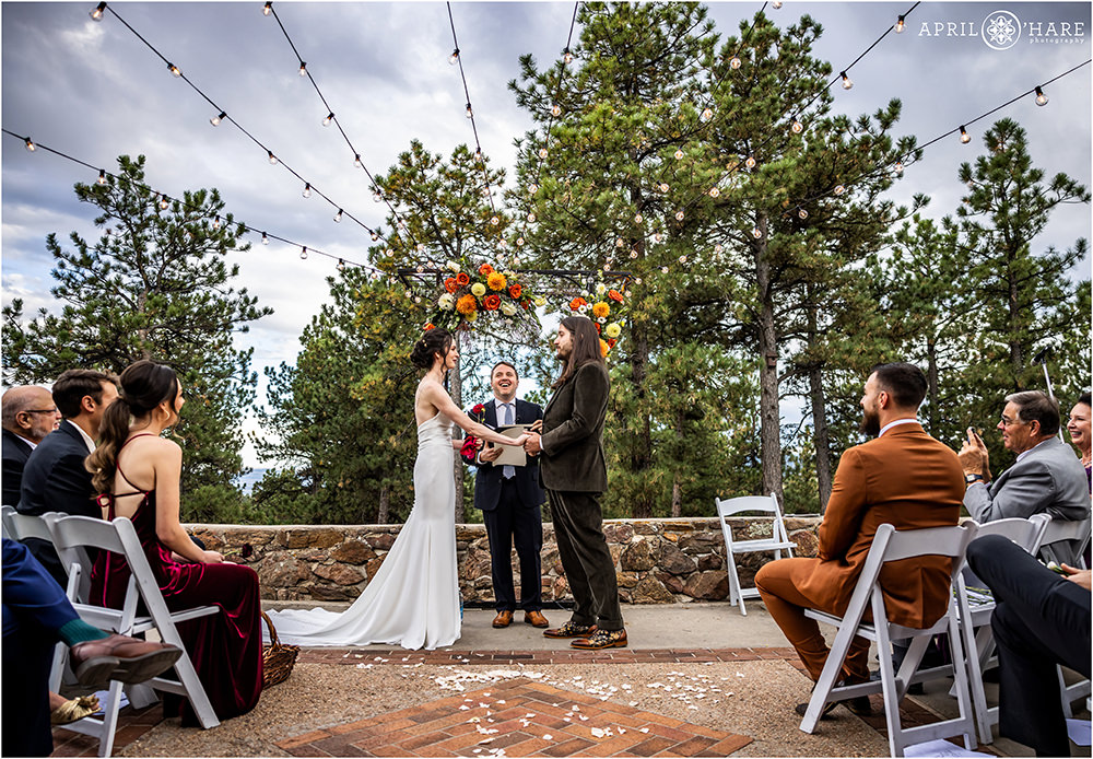 Wide angle view of bride and groom getting married on the outdoor patio at Boettcher Mansion in Golden CO