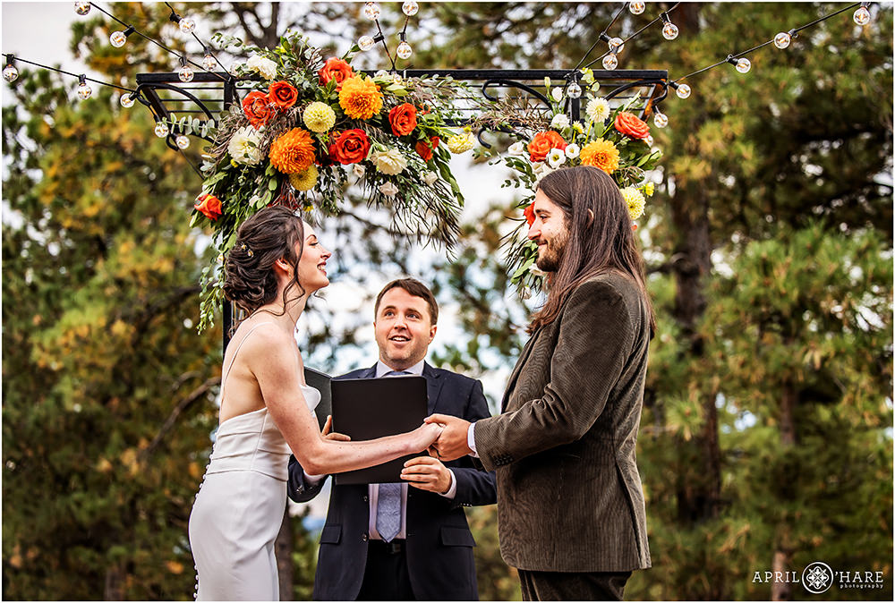 Bride and groom smile at each other as they get married outside in a woodsy wedding at Boettcher Mansion in Colorado