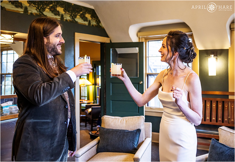 Bride and groom cheers with a drink after their wedding ceremony in the upstairs Aspen Room at Boettcher Mansion