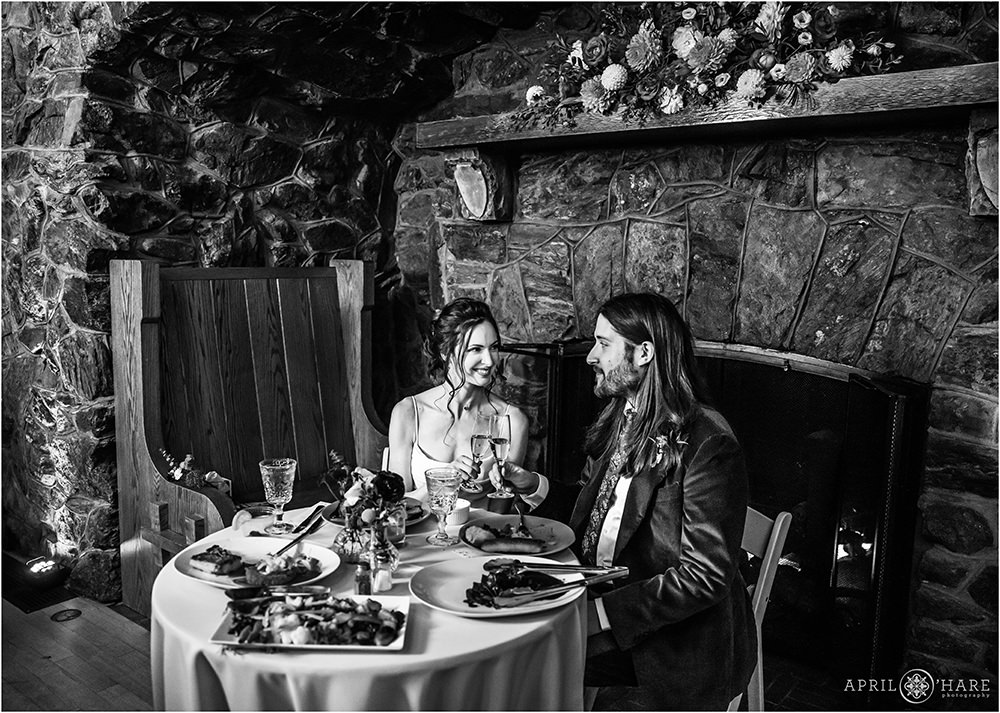 B&W reception photo of the bride and her groom enjoying dinner together on their wedding day in the Fireside Room at Boettcher Mansion