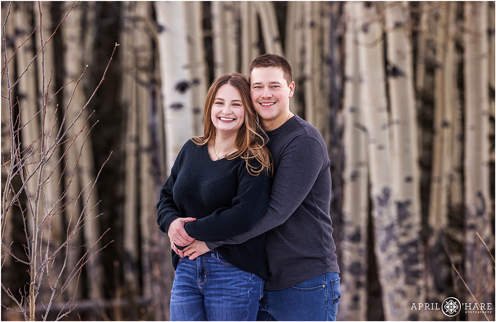 Cute couples portrait during winter with aspen tree backdrop behind them in Evergreen Colorado