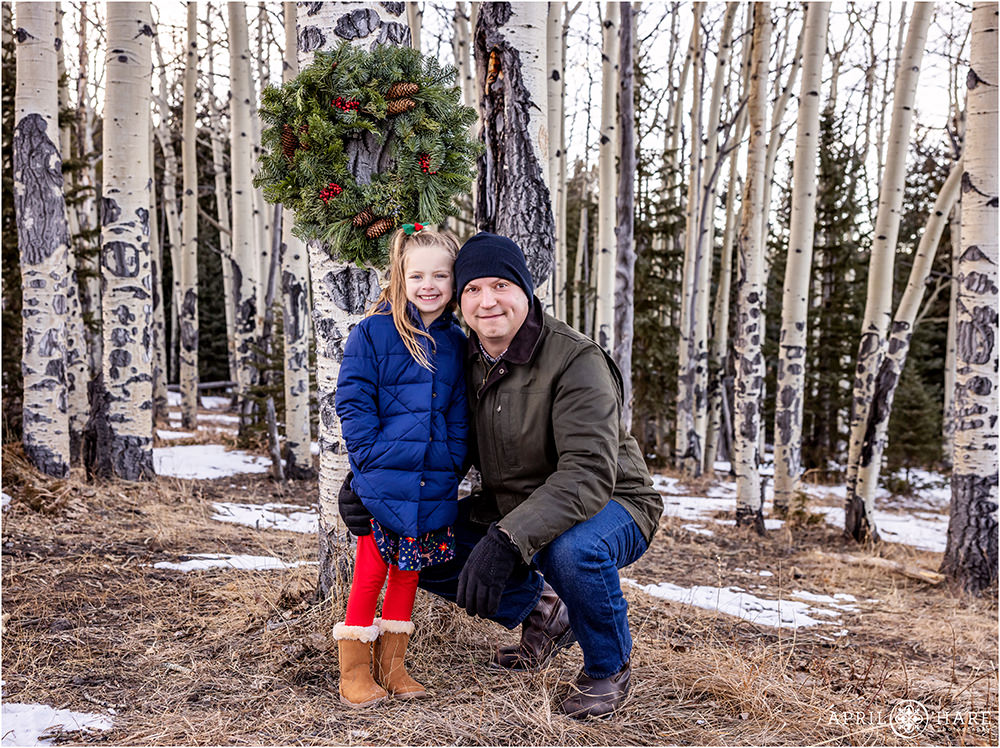 Girl with her dad pose for family Christmas photos in the woods of Evergreen CO