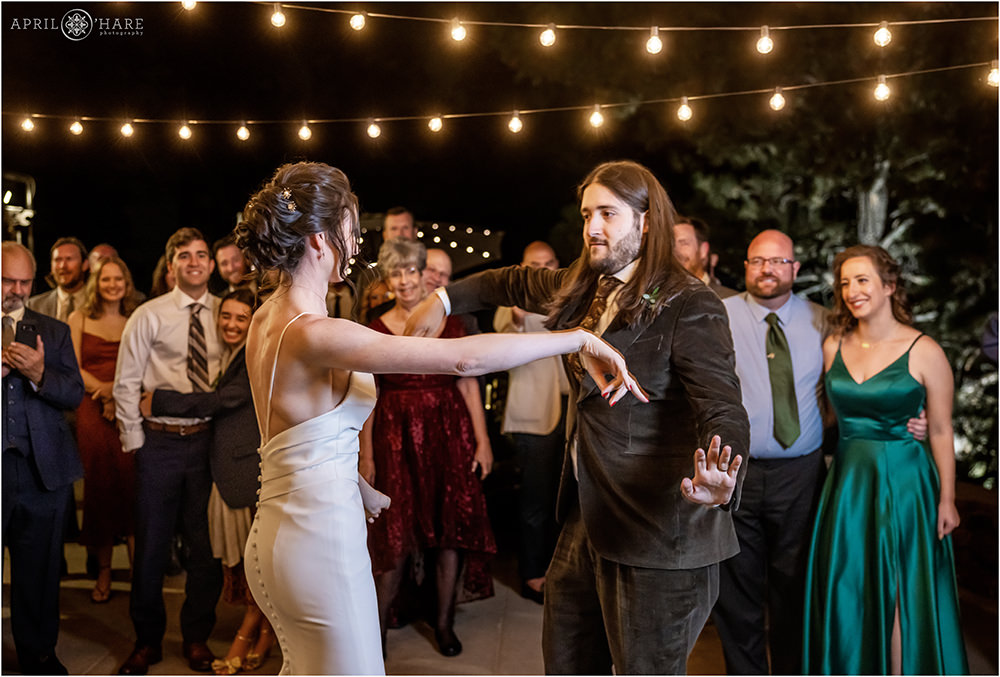 Couple have fun during their first dance under the patio string lights at Boettcher Mansion
