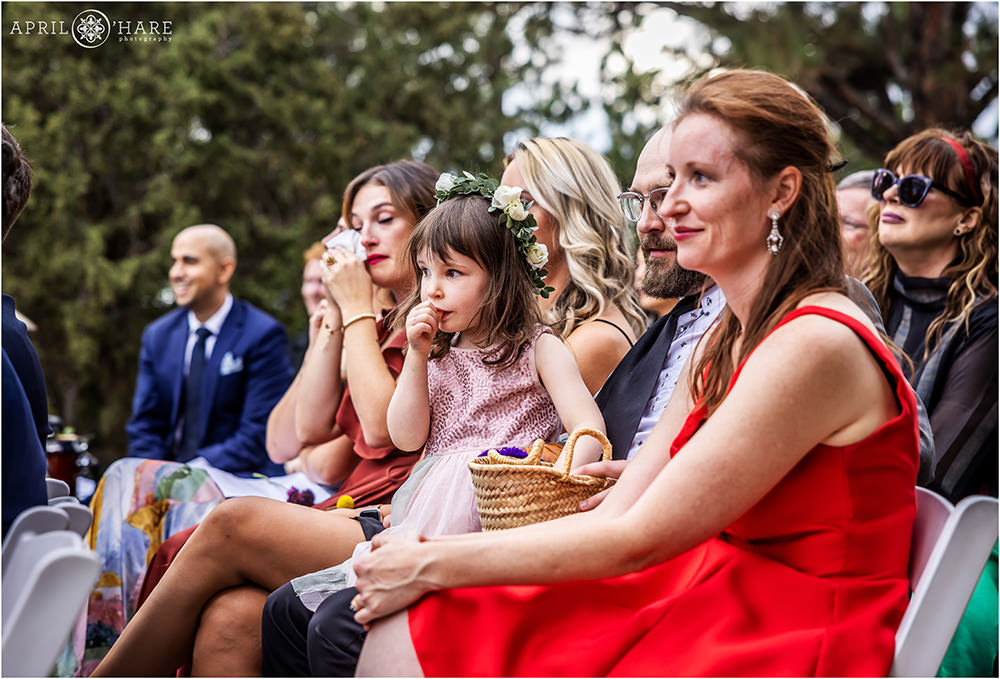 Flower girl looks on at the wedding ceremony while sucking her thumb at a Boettcher Mansion wedding in Colorado