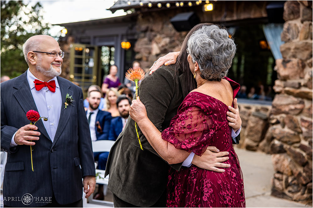 Groom hugs his mom after walking down their aisle with his parents at Boettcher Mansion