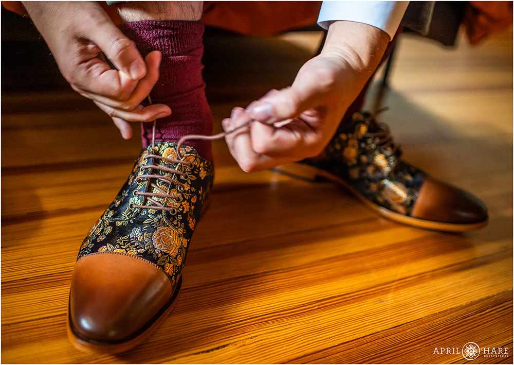 Groom ties his cool orange floral shoes on his wedding day in Colorado