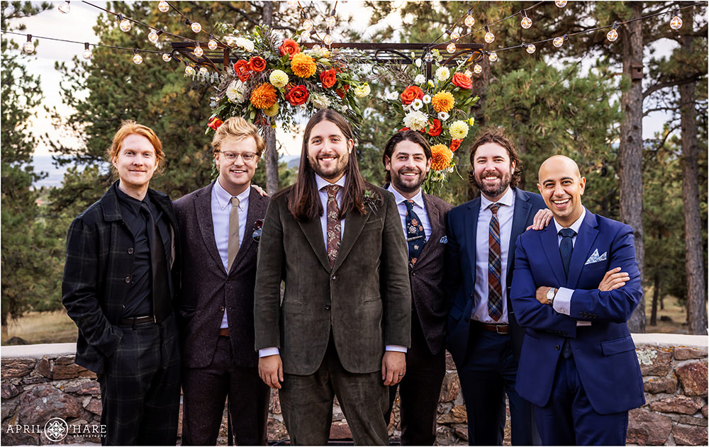 Groom portrait with his friends and bandmates in front of the orange floral backdrop at Boettcher Mansion