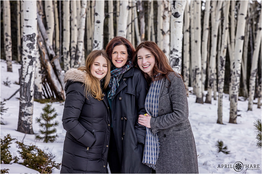 A mom with her two adult daughters pose in a pretty aspen tree forest in Evergreen Colorado