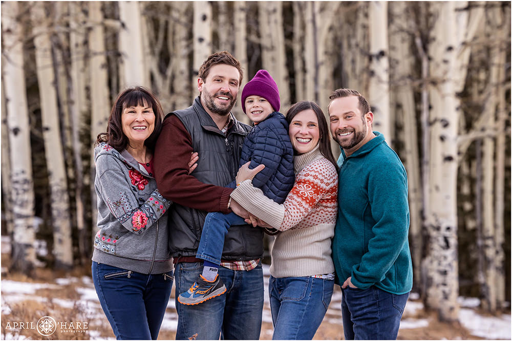 Extended family photo in front of a grove of aspen trees during winter in Colorado