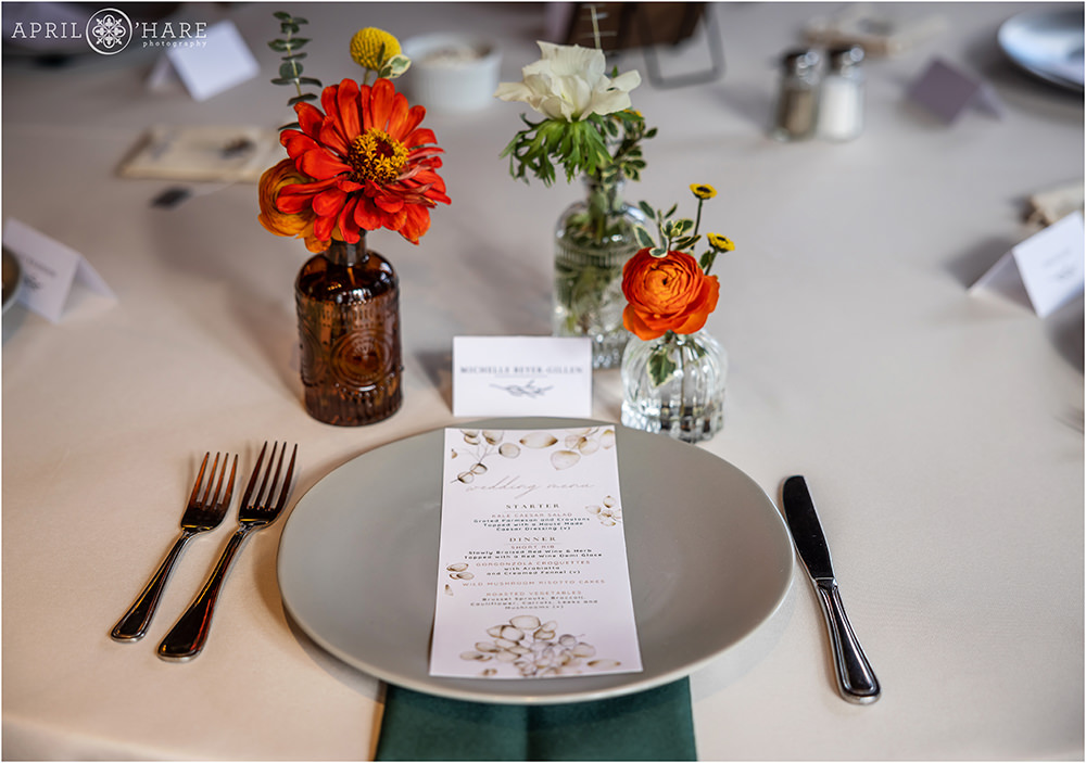 Table setting with custom printed menu at a Boettcher Mansion wedding with orange florals and green linens