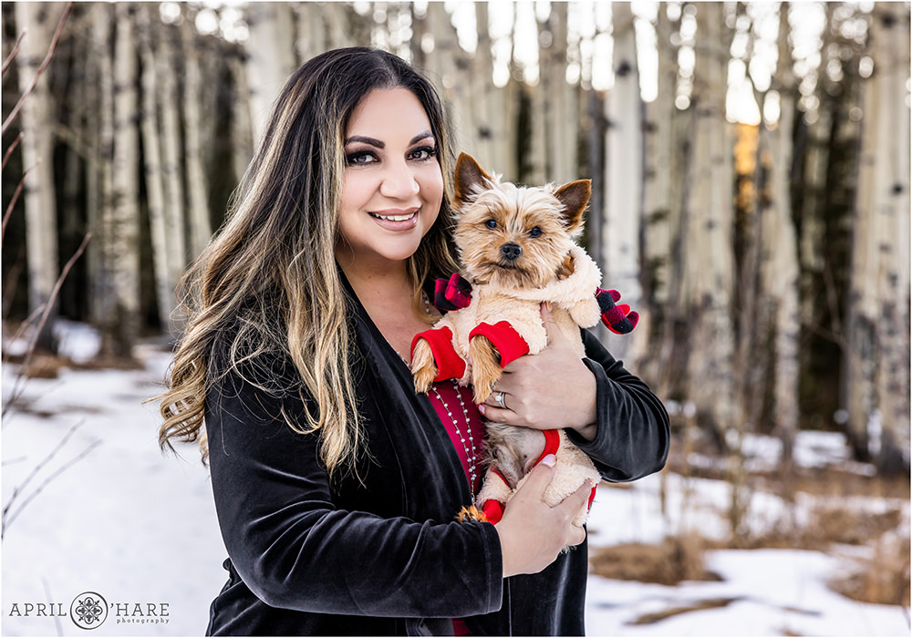 Beautiful woman with her sweet old Yorkie Dog wearing a holiday onesie in Colorado during winter
