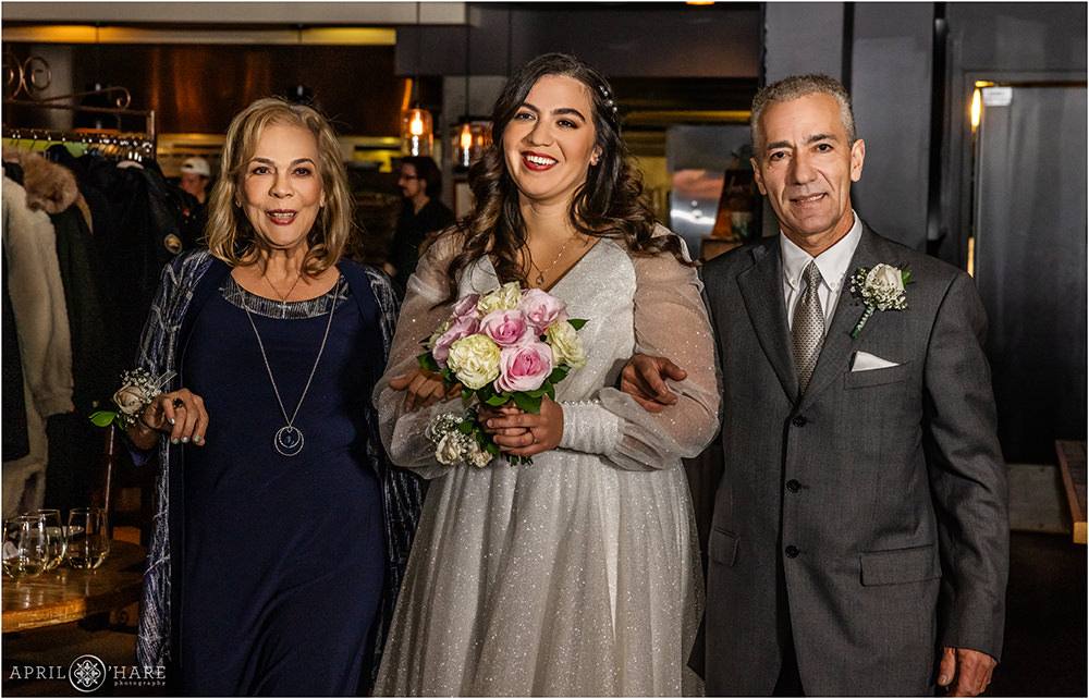 Bride smiles at her groom as she walks down the aisle with her parents on their New Year's Eve wedding at Coohills