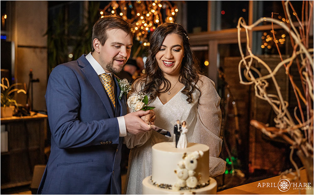 Bride and groom cut their white wedding cake with a vintage family heirloom cake topper on it