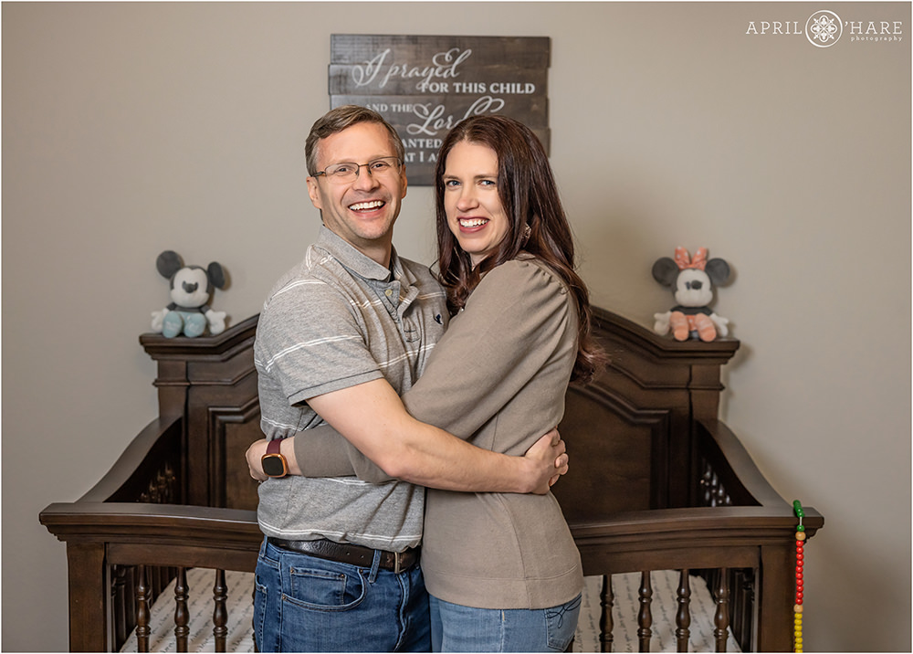 Couple waiting to adopt photographed in front of a crib at their home in Littleton Colorado