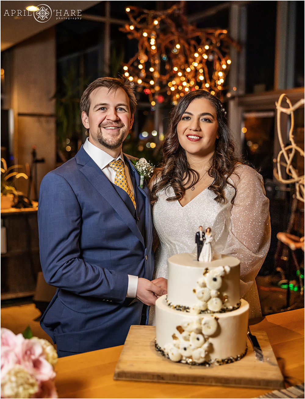 Bride and groom with their cute white wedding cake with a vintage cake topper on it