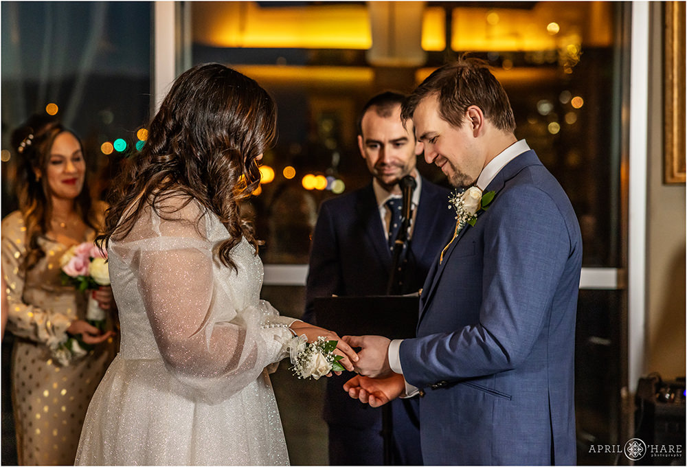 Wedding couple exchange rings in front of the huge picture windows at their NYE wedding at Coohills in Denver