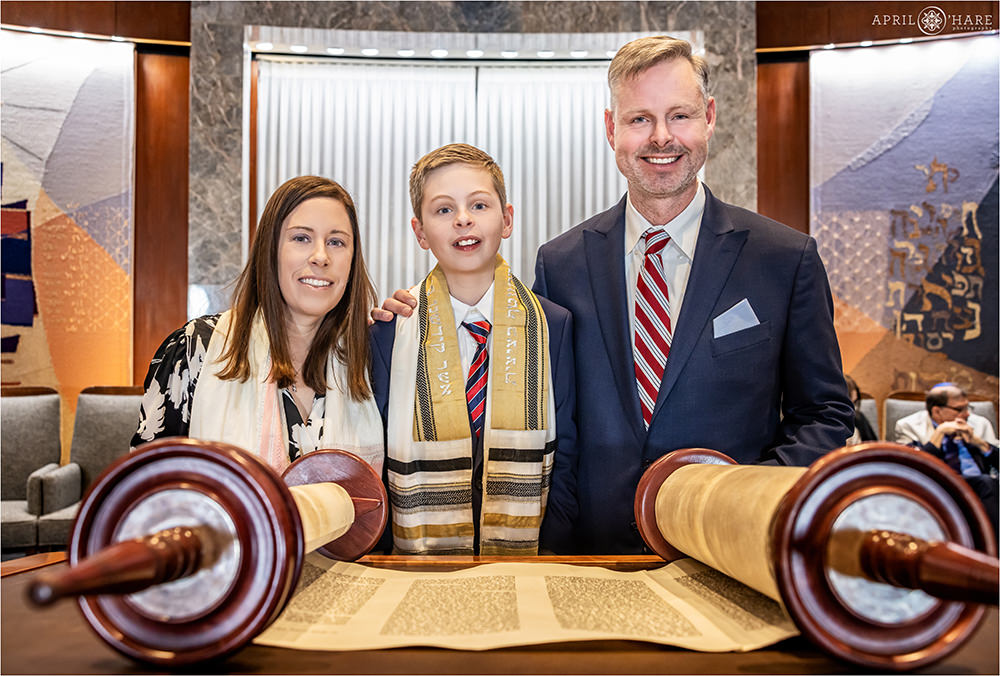 Bar Mitzvah boy with his parents with the Torah scroll open at his bar mitzvah rehearsal at Temple Sinai in Denver, CO