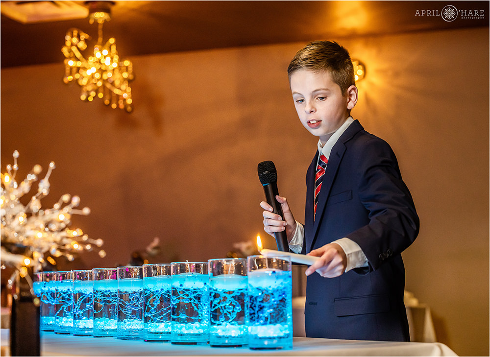 Bar mitzvah boy lights his blue candles at the candle lighting ceremony at his bar mitzvah party at Curtis Ballroom in Denver, CO