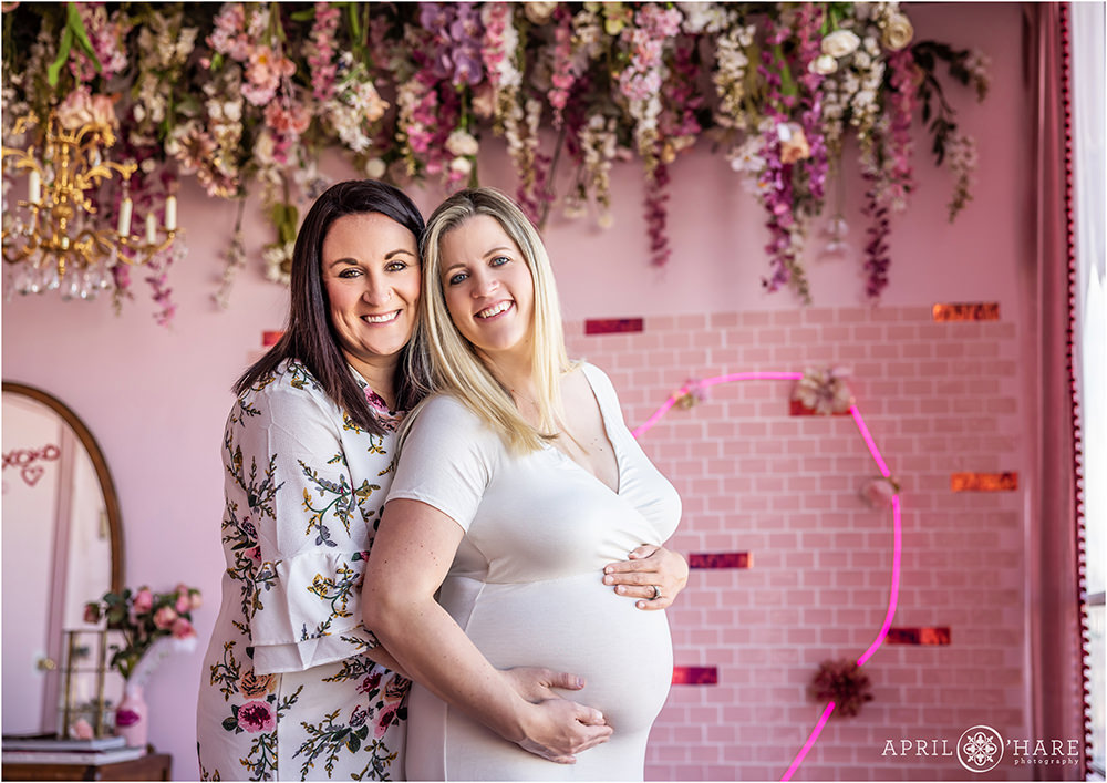 Beautiful indoor maternity photography session in a pretty pink Valentine's Day studio styled set in Denver for a lesbian couple in Denver