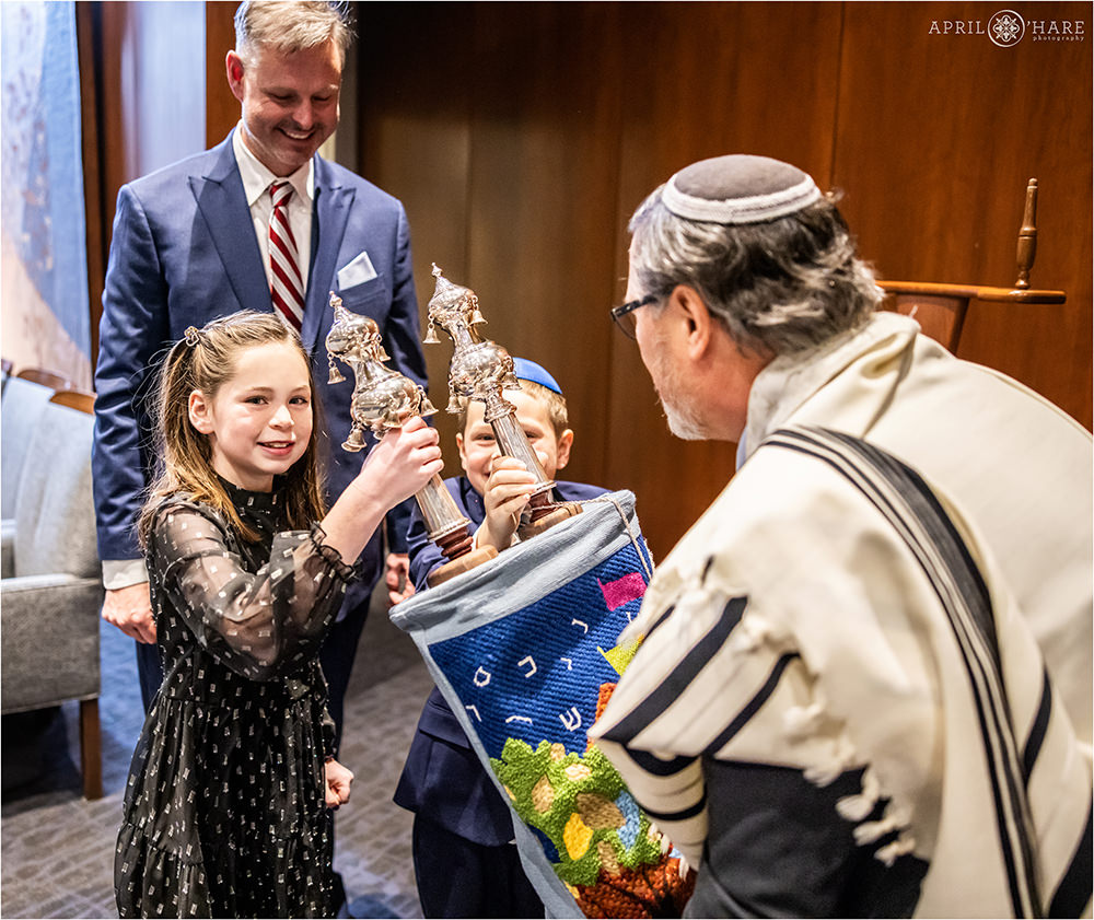 Siblings of the bar mitzvah boy help with the silver keter part of the Torah at this brother's bar mitzvah rehearsal at Temple Sinai