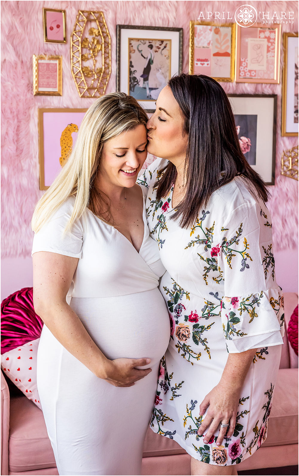 Two moms are photographed at their maternity session in a pretty pink styled set in Denver CO