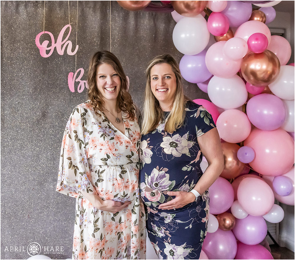 Two pregnant sisters pose for a photo together at a pretty purple and pink baby shower in Denver CO