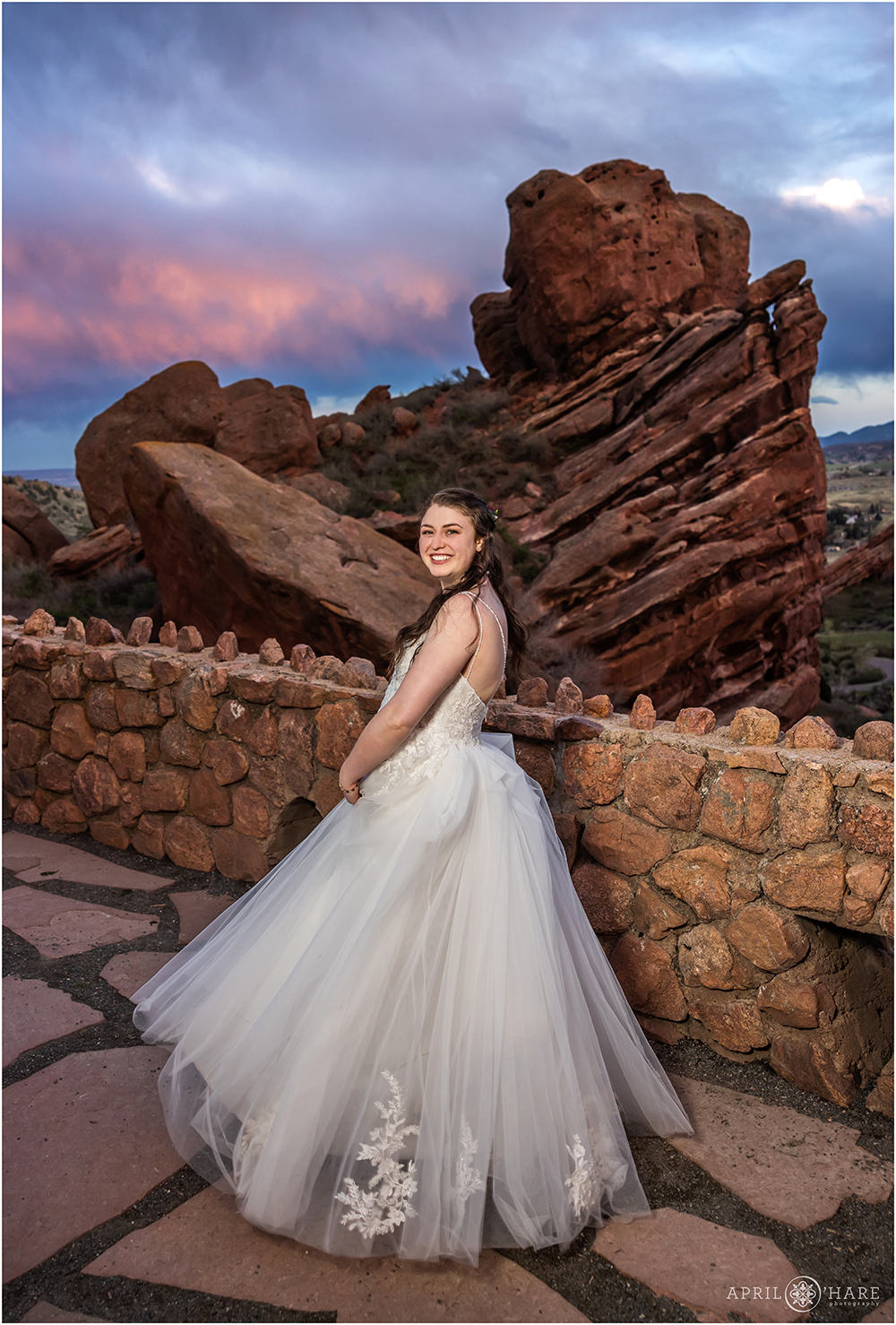 Bride twirls in her dress a little bit at sunset on her wedding day at Red Rocks in Colorado