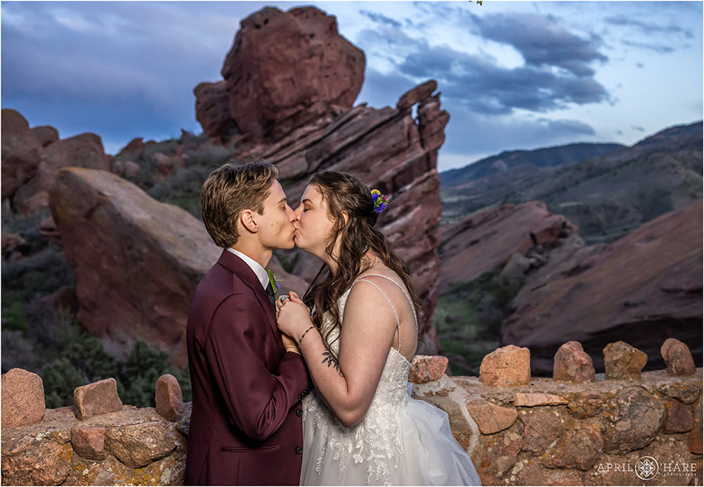 Bride and groom kiss at dusk on their wedding day at Red Rocks