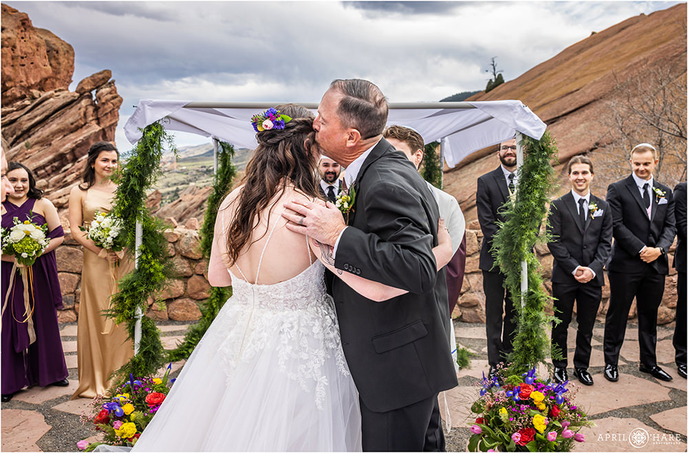 Bride's father kisses her before giving her away at her Red Rocks wedding in Colorado