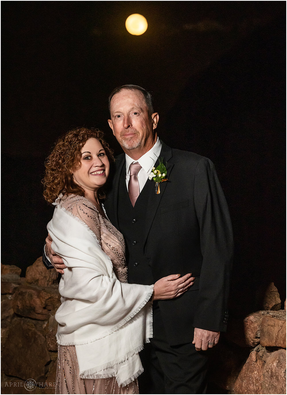 Mother and father of the bride get a portrait at night with the full moon at Red Rocks wedding