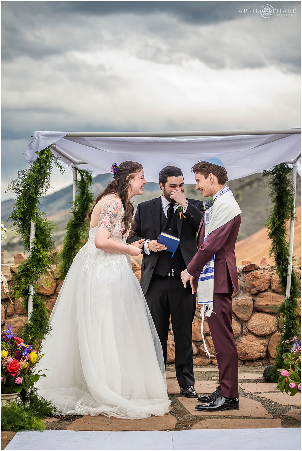 Bride and groom laugh together during their wedding ceremony at the Red Rocks Trading Post Backyard