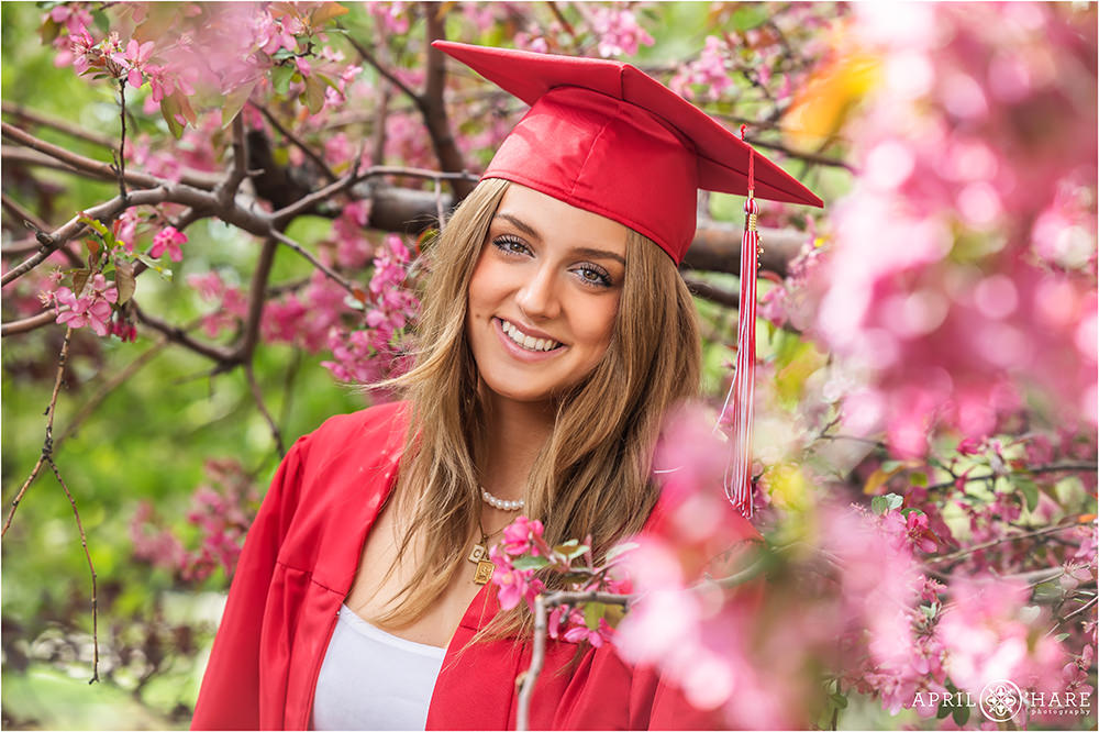 Beautiful grad photo in cap and gown with pink flower blossoms in Colorado