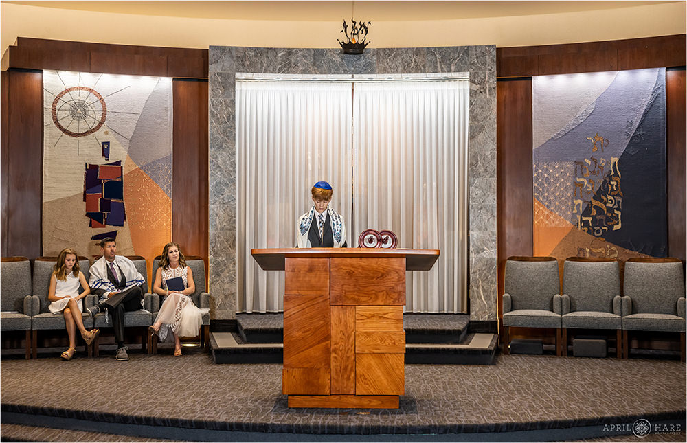 Bar Mitzvah boy does a reading as his family sits and watches at Temple Sinai in Denver CO